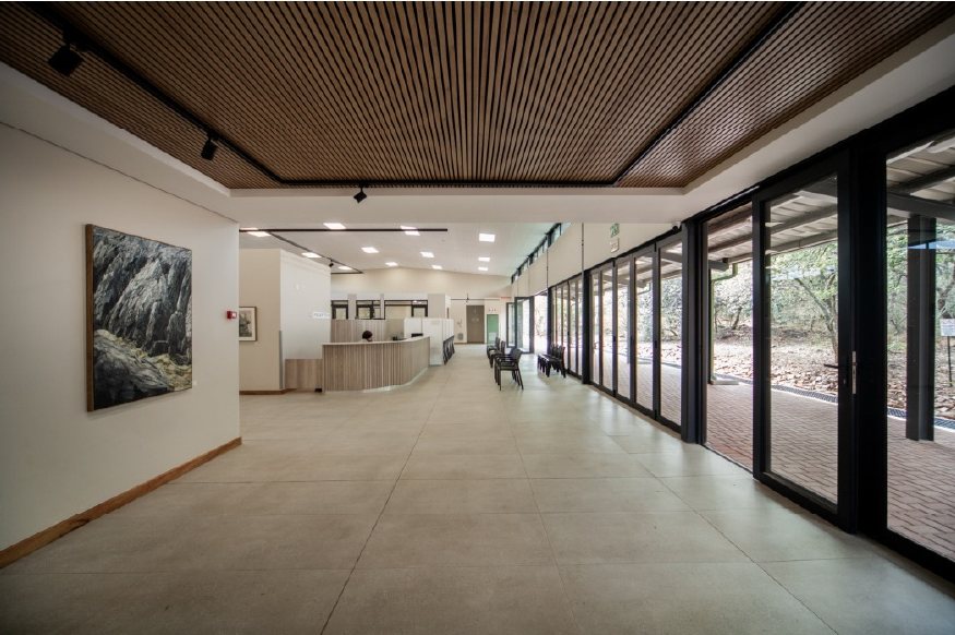 Gallery space with a framed landscape photograph, a timber slatted ceiling and full-height glazed doors opening to a covered walkway.