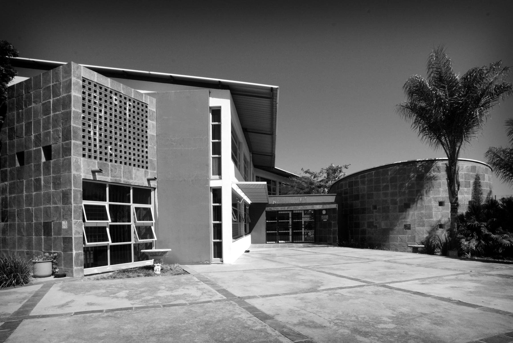 Two-storey rendered building with a slate-clad screen wall and a curved garden wall, seen across the forecourt.