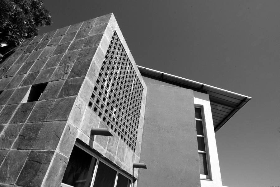 Slate-clad screen wall with a perforated panel beside a rendered facade.