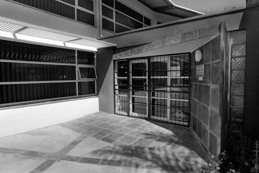 Entrance courtyard with slate paving, a clad entrance wall and glazed doors.