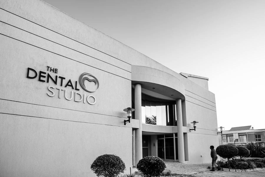 Entrance front of the Dental Studio with building signage, a curved porch and columns.
