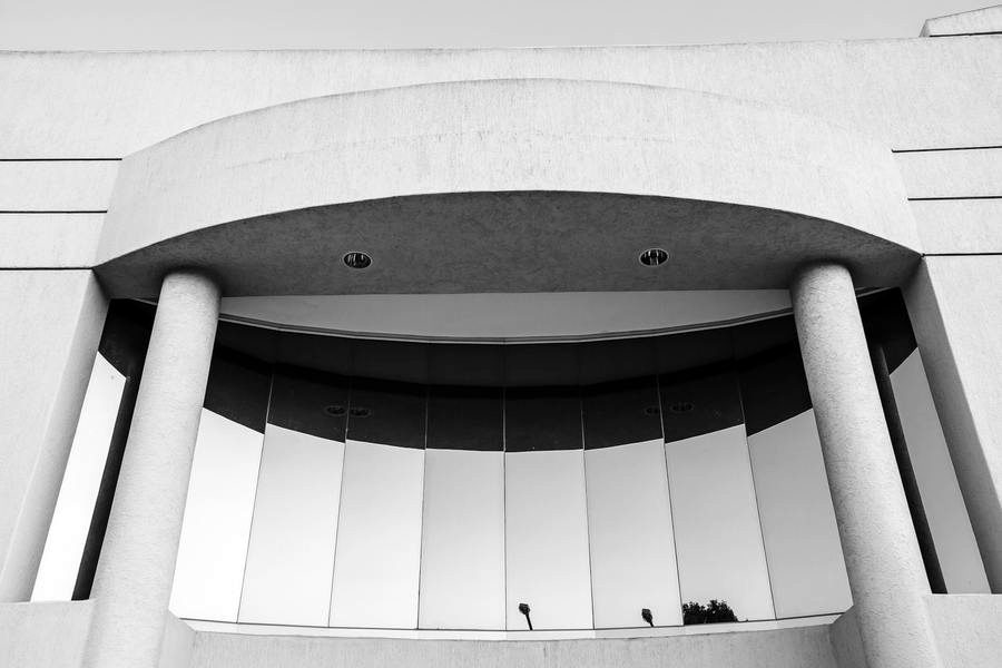 Curved portico with slender columns and a glazed screen above.