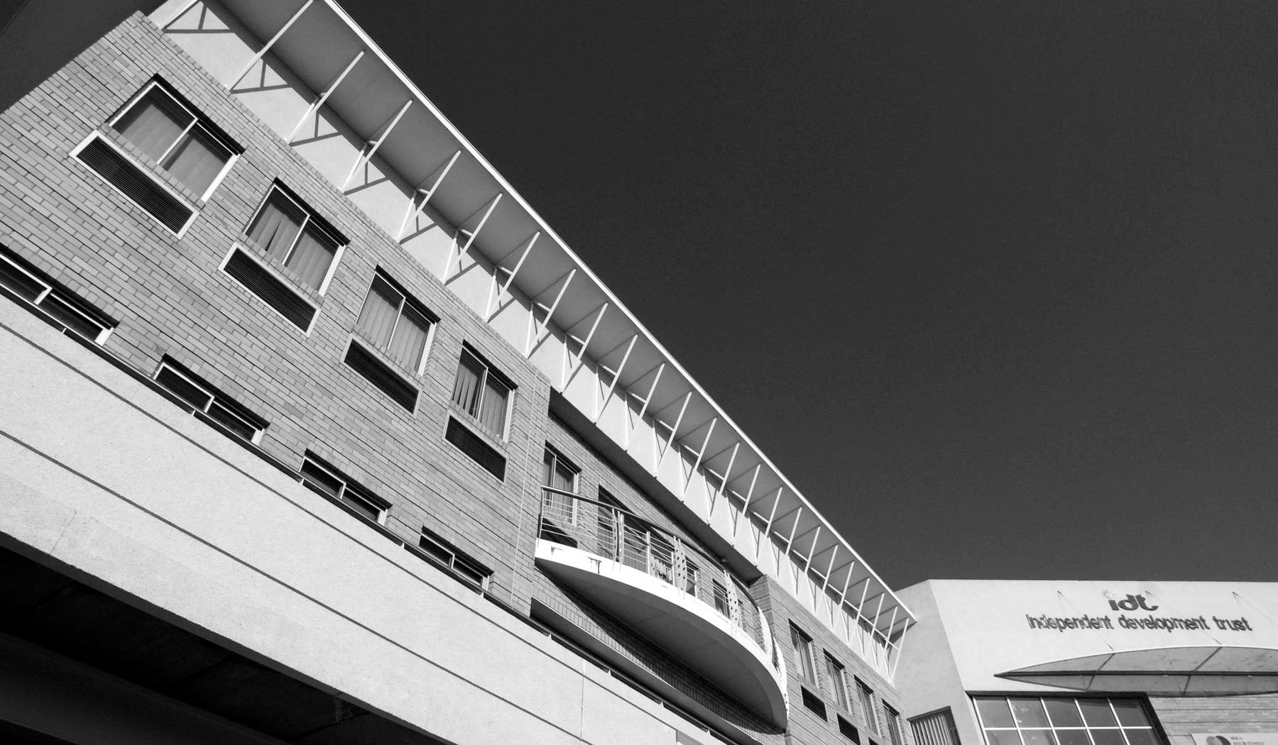 Face-brick office building with a curved balcony band and a continuous roof canopy, seen at a low angle.