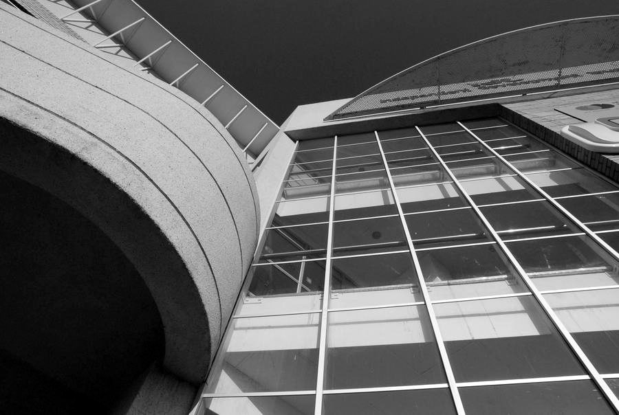 Curved concrete entrance feature and the glazed atrium front of the office building.