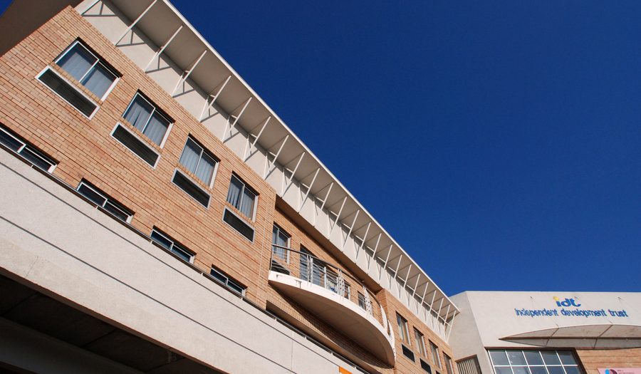 Face-brick facade with a continuous roof canopy and curved balcony band, seen from below.