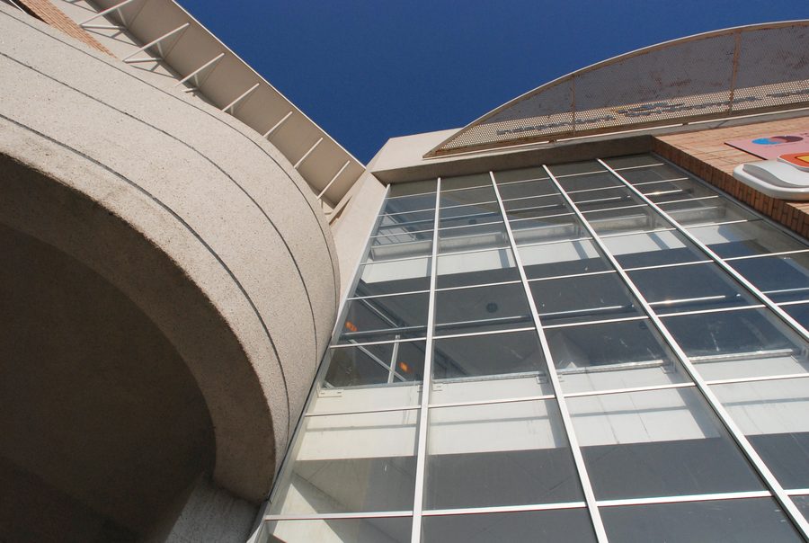 Curved concrete balcony band and the glazed atrium front, seen from below.
