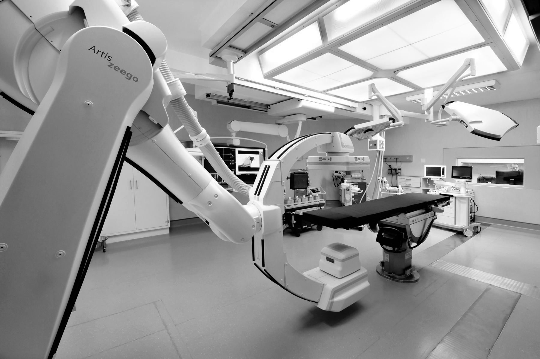 Hybrid operating theatre with a ceiling-mounted imaging arm, monitors and an operating table.
