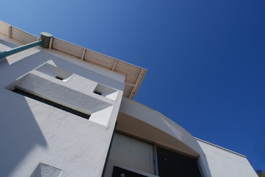 Projecting canopy and window recesses on the white rendered facade, seen from below.