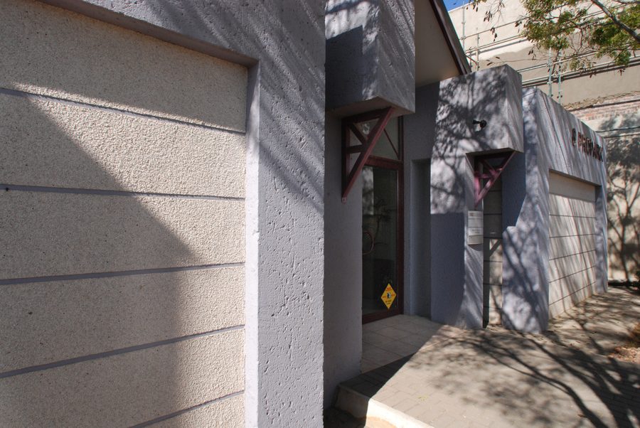 Textured plastered wall with horizontal grooves beside the glazed entrance.