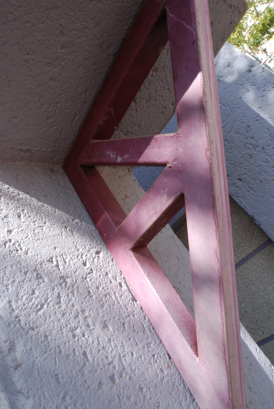 Red steel frame of the glazed gable against the textured plaster wall.